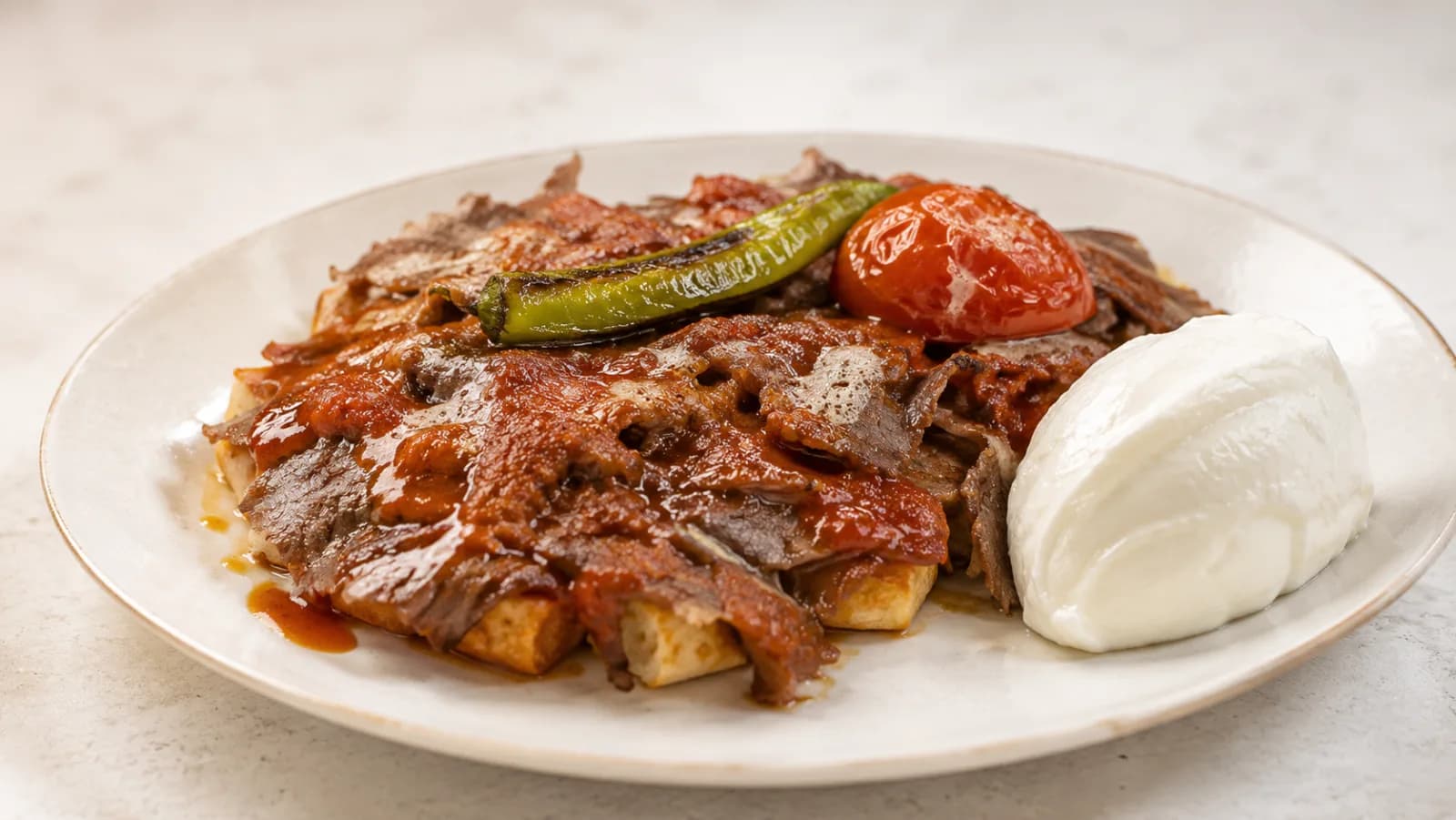Bursa İskender Kebap — Döner dilimlerinin kızarmış pide üzerine dizilip domates sosu, eritilmiş tereyağı ve yoğurtla servis edildiği, Bursa il…